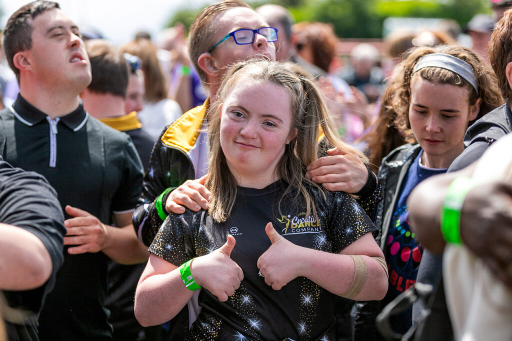 Photo of a happy girl smiling at the camera standing in the crowd at a concert from Able Fest inclusive events