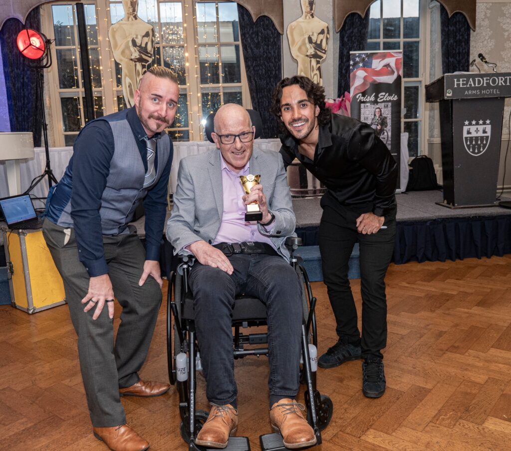Photo of the Able Events founders together with a man in a wheelchair holding a trophy