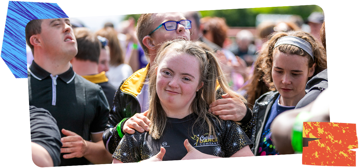 Young woman smiling at camera as she stands in a big crowd at an inclusive event run by Able Events